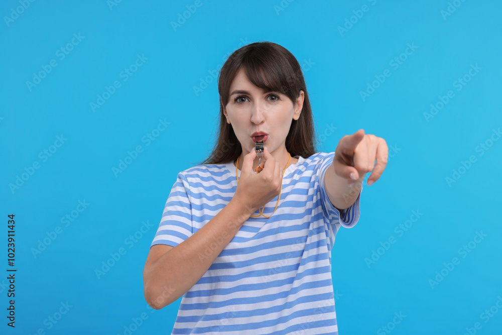 Woman blowing whistle on light blue background Woman blowing whistle on light blue background