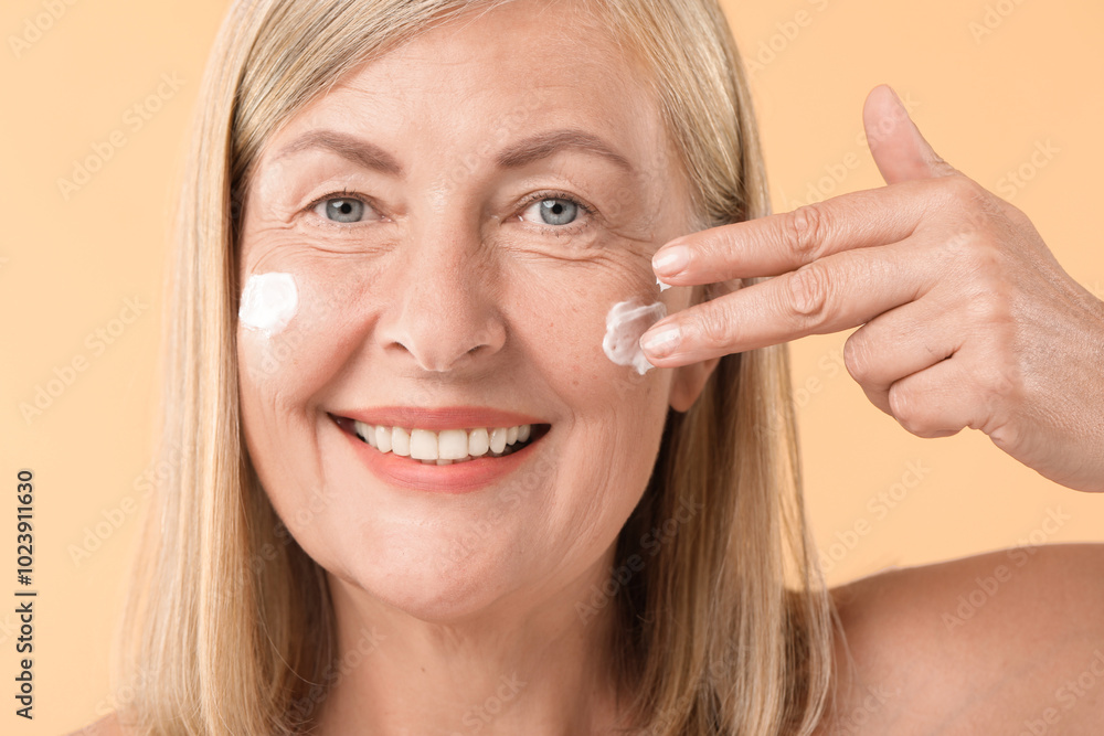 Senior woman applying face cream on beige background, closeup Senior woman applying face cream on beige background, closeup