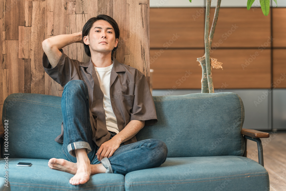 Fototapeta premium 家のリビングで退屈な時間を過ごす若いアジア人男性（つまらない・憂鬱・無気力・ダルい・疲労・鬱病） 