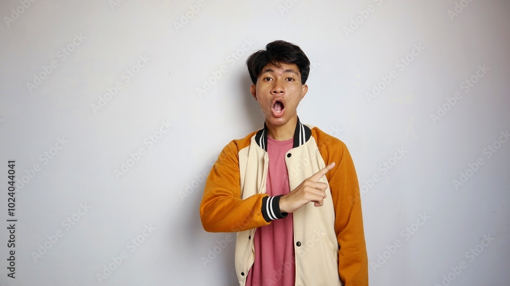 casual shocked young handsome Asian man wearing a jacket giving a gesture pointing upwards casual shocked young handsome Asian man wearing a jacket giving a gesture pointing upwards