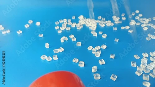 virgin polymer granules, falling like flowing water splashing into a mound, isolated on blue background, for industrial plastic product profile video