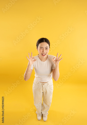 Full body image of young Asian girl posing on yellow background photo