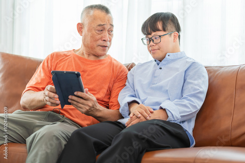 Asian senior man and grandson using tablet smartphone doing a video call in living room, Grandparents and grandson having fun together at home