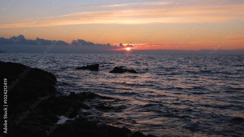 Purple sea sunset. The sea water ripples at sunset. The concept of a summer vacation on the seashore. Beautiful sunset light. A calm, peaceful atmosphere of relaxation, privacy. Silhouettes of stones Purple sea sunset. The sea water ripples at sunset. The concept of a summer vacation on the seashore. Beautiful sunset light. A calm, peaceful atmosphere of relaxation, privacy. Silhouettes of stones