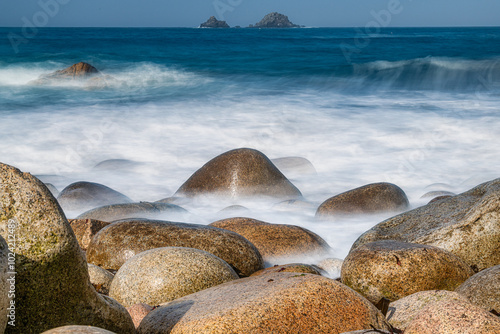 Porth Nanven in Cornwall, with the Brison Rocks in the distance, the smoke like sea created by a long exposure. photo