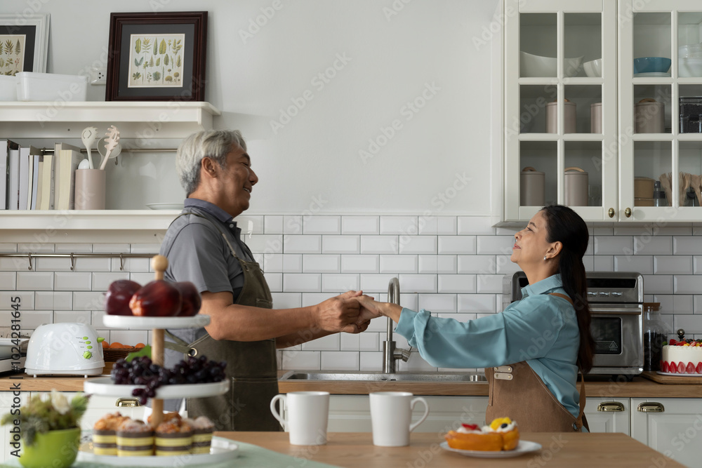 Asian Senior Couple Dancing Joyfully in Kitchen Asian Senior Couple Dancing Joyfully in Kitchen