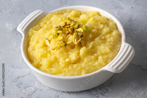 Sweet yellow Turkish dessert cheese halva Hosmerim on the white plate in the kitchen.