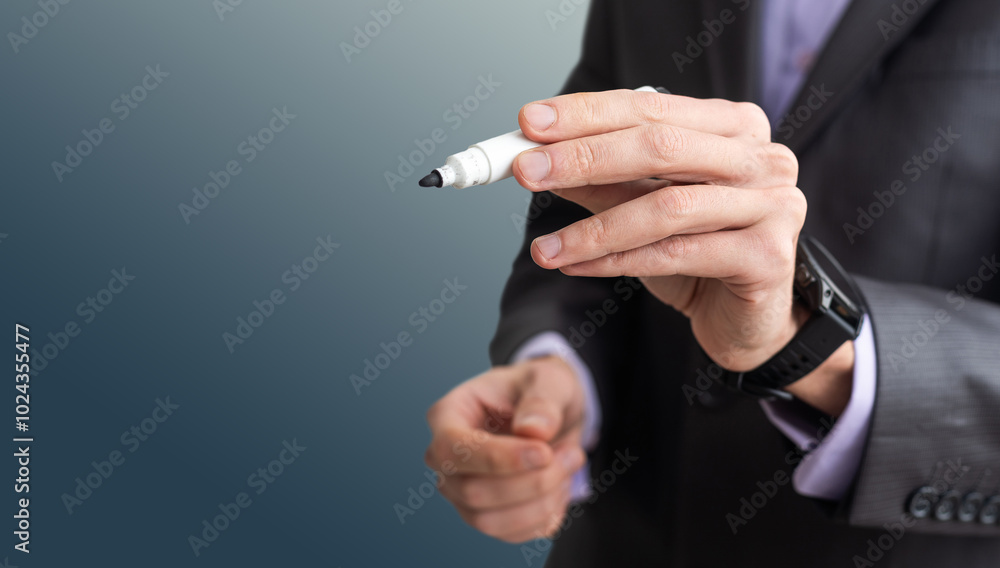 Man writes something on screen. Businessman raised his hand to screen. Concept - businessman writes on a virtual screen. Businessman held out a pen to camera. Guy in a dell suit on black background.