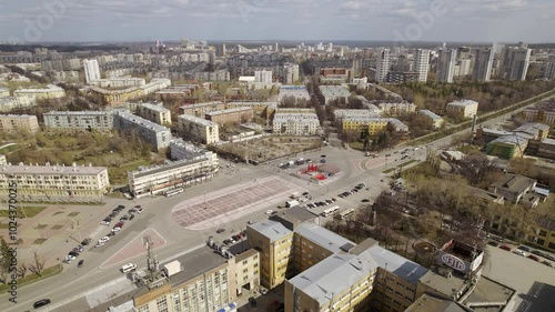 Aerial view of traffic in the city on a street with a roundabout and a square. Low-rise buildings