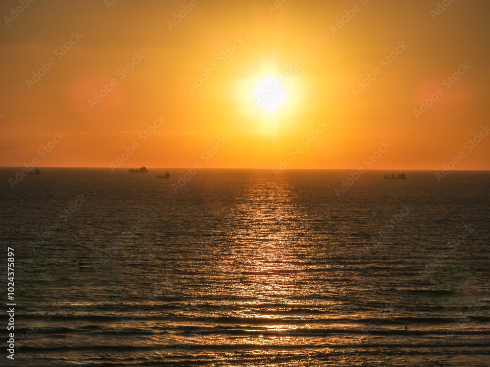 Golden sunset over the sea with a distant ship on the horizon Golden sunset over the sea with a distant ship on the horizon