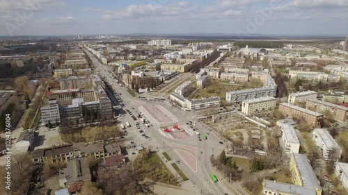 Aerial view of traffic in the city on a street with a roundabout and a square. Low-rise buildings