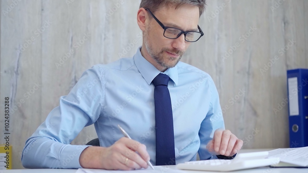 Male accountant concentrating on calculating costs with focus and precision