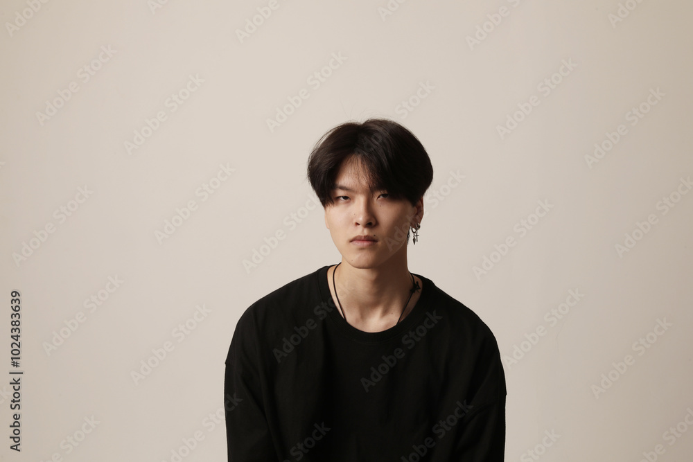 Portrait of unhappy young Asian man wearing casual t-shirt posing indoor over white background. Portrait of unhappy young Asian man wearing casual t-shirt posing indoor over white background.