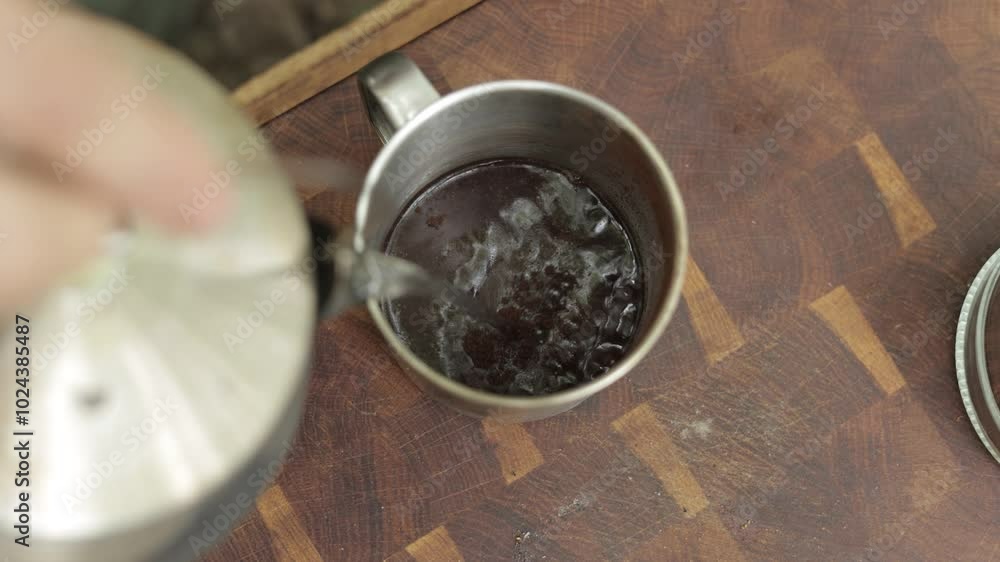 A person pours hot water into a cup of coffee grounds. The coffee is prepared outdoors in a camping setting by the lake. The pumpkin is roasted and served outdoors. Perfect for fall. A person pours hot water into a cup of coffee grounds. The coffee is prepared outdoors in a camping setting by the lake. The pumpkin is roasted and served outdoors. Perfect for fall.