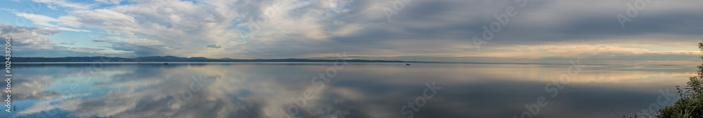 ampissima composizione panoramica con vista sul golfo di Trieste, nel mare Adriatico, al tramonto, in autunno, guardando verso la costiera di Trieste, sotto un cielo nuvoloso che si riflette nel mare ampissima composizione panoramica con vista sul golfo di Trieste, nel mare Adriatico, al tramonto, in autunno, guardando verso la costiera di Trieste, sotto un cielo nuvoloso che si riflette nel mare