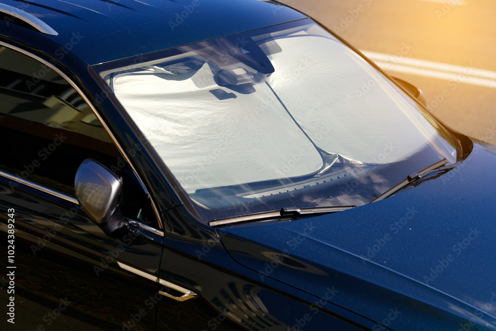 Parked car with windshield sunshade. Reflective car windshield sun shade made of aluminium foil, protect against intense heat and reduce interior temperatures. Heat and UV protection