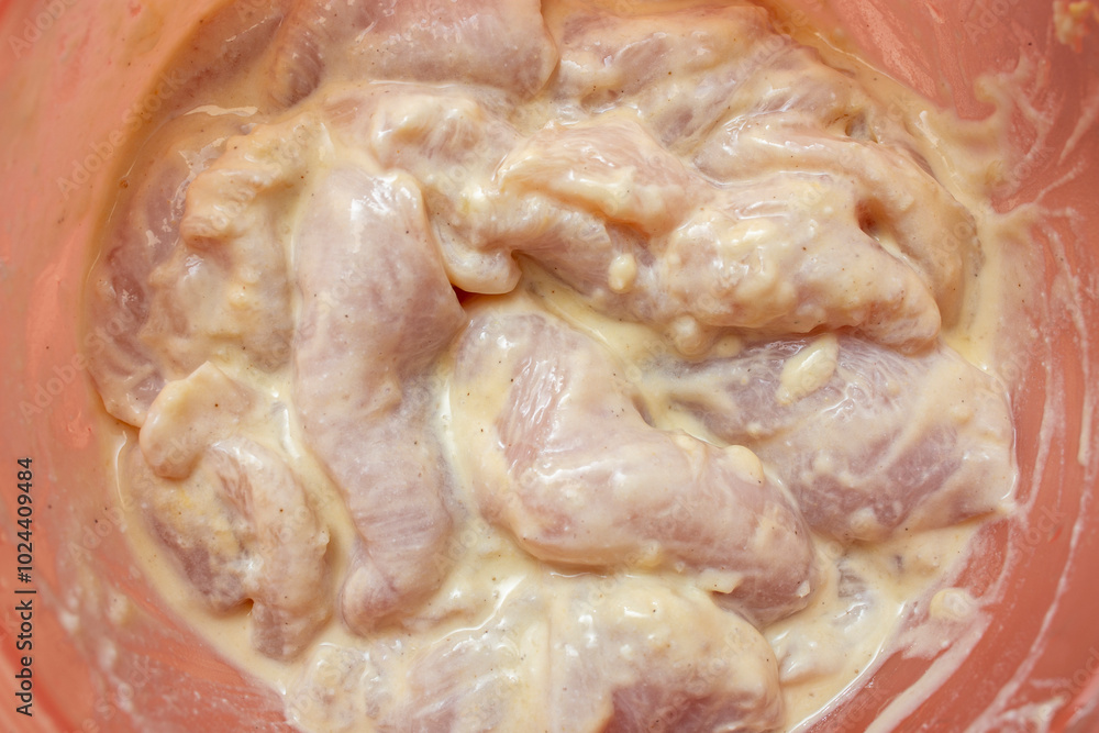 Chicken breast meat with yogurt marinade, in a pink bowl selective focus close up Chicken breast meat with yogurt marinade, in a pink bowl selective focus close up