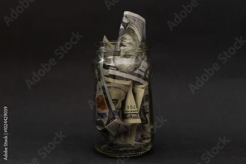 Many 100 US dollars bank notes in a glass jar isolated photo