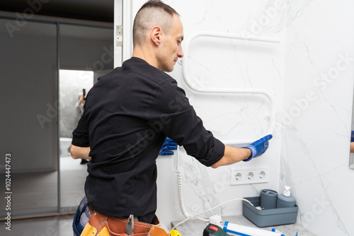 A worker is installing a heating element in the towel warmer in the bathroom.