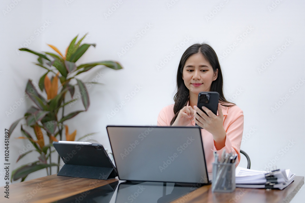 Businesswoman using mobile phone while working by connecting technology and synchronizing between devices. Businesswoman using mobile phone while working by connecting technology and synchronizing between devices.
