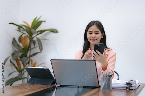 Businesswoman using mobile phone while working by connecting technology and synchronizing between devices.