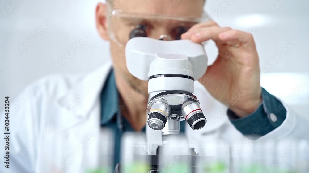 Man scientist with protective glasses using microscope in laboratory. Microbiology science concept Man scientist with protective glasses using microscope in laboratory. Microbiology science concept