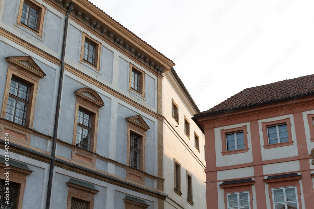 A large building that features numerous windows is located adjacent to a smaller and more modestly sized structure nearby A large building that features numerous windows is located adjacent to a smaller and more modestly sized structure nearby