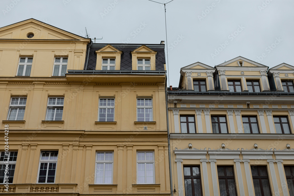 A yellow building that features a distinctive black roof is situated right next to another yellow building that also shares similar architectural elements A yellow building that features a distinctive black roof is situated right next to another yellow building that also shares similar architectural elements