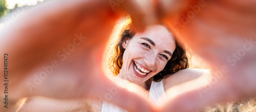 Foto Smiling woman making a heart shape with hands - Pretty joyful woman laughing at