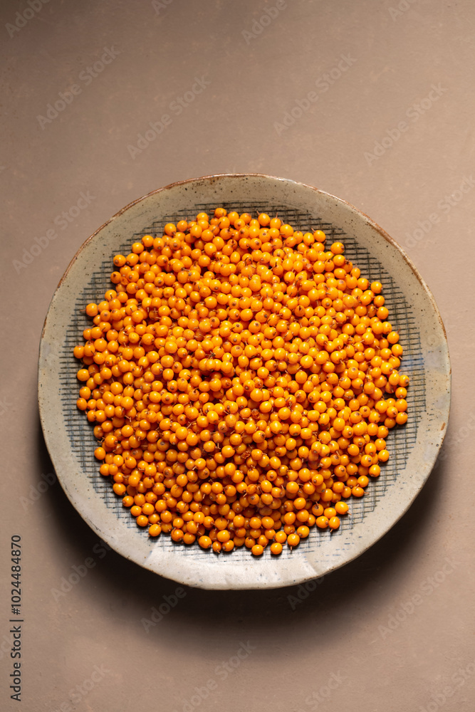 A plate with orange berries stands on a table with a gray napkin, top view A plate with orange berries stands on a table with a gray napkin, top view