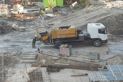 Aerial view of busy industrial under construction site workers working with cranes and excavators. Top view of precast concrete slap floor full of steel. Development high rise architecture building.