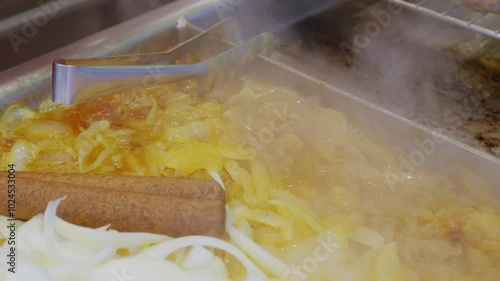 A Man Making Hot Dogs with onions and sausage