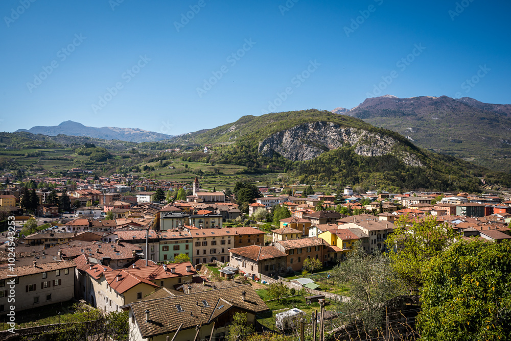 Fototapeta premium A stunning view of the town of Mori, Trentino, Italy, captured from Monte Albano via ferrata. The town's red-tiled roofs and surrounding hills create a picturesque scene amidst the mountains.