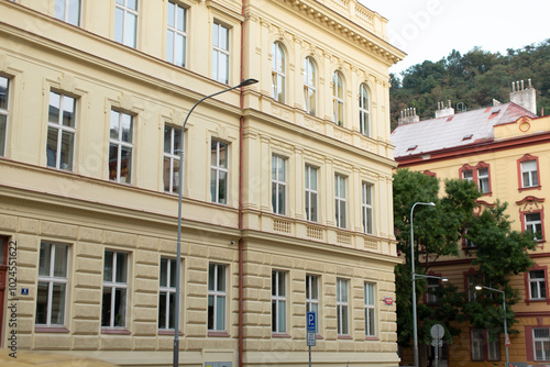 In front of a large building that boasts an abundance of windows, there stands a street light illuminating the area at night