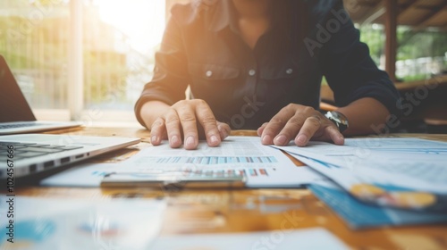 Focused businessman at desk with financial documents and laptop displaying earnings reports, conveying determination and attention to financial data analysis.