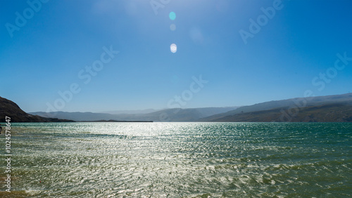 view of the Chirkeyskoye reservoir with the color of turquoise water against a background of blue sky and mountains photo