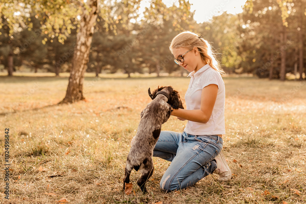 Teenager girl with glasses playing on grass with her little dog, brown cocker spaniel puppy, outdoors, in a park. Teenager girl with glasses playing on grass with her little dog, brown cocker spaniel puppy, outdoors, in a park.