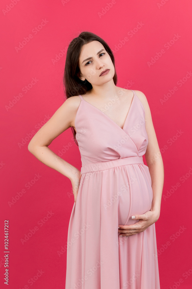 Pregnant woman with a pain in her back on colored Background isolated Pregnant woman with a pain in her back on colored Background isolated