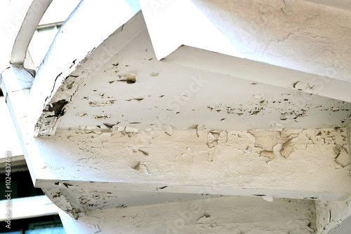 Tablou pe pânză Aging stucco and cracked white paint on building's balcony, deterioration of exterior materials over time