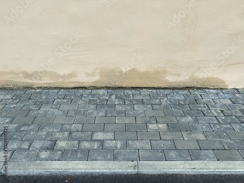 Photos A grey cobblestone sidewalk next to an old plaster wall