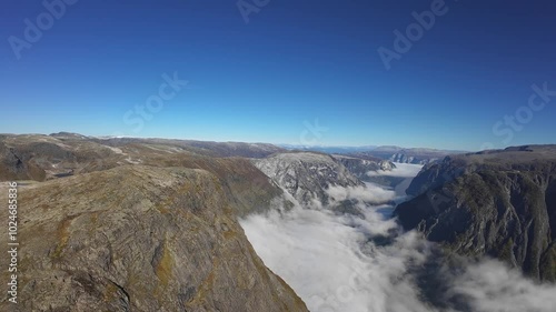 Forward aerial over Naeroyfjord, flying toward Aurlandsfjord and Breiskrednosi with Bakkanosi to the left. Sunny with cloud inversion below photo