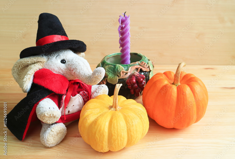 Cute elephant doll in wizard costume with a pair of pumpkins and a seasonal decoration Cute elephant doll in wizard costume with a pair of pumpkins and a seasonal decoration
