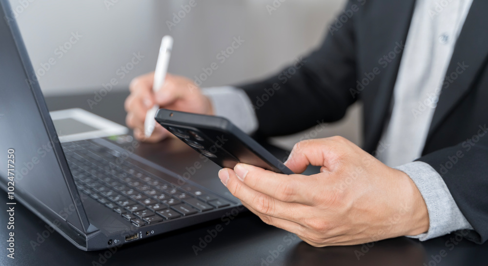 Businessman using mobile smart phone and online working on laptop computer Businessman using mobile smart phone and online working on laptop computer