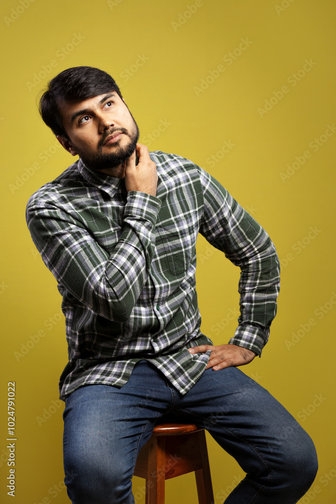 man sitting, with hand touching neck and looking up man sitting, with hand touching neck and looking up