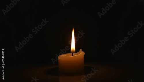 Glowing candle flame illuminating darkness