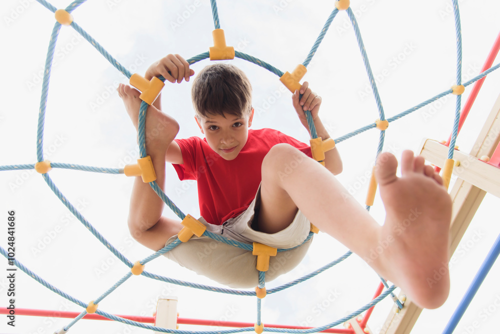Happy boy playing and hanging on ropes on playground. Children's exercises for health and concentration Happy boy playing and hanging on ropes on playground. Children's exercises for health and concentration