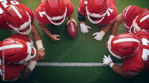 A close-up view of football players in red uniforms engaged in a strategy huddle on the field. They exhibit teamwork and focus while planning their next move.