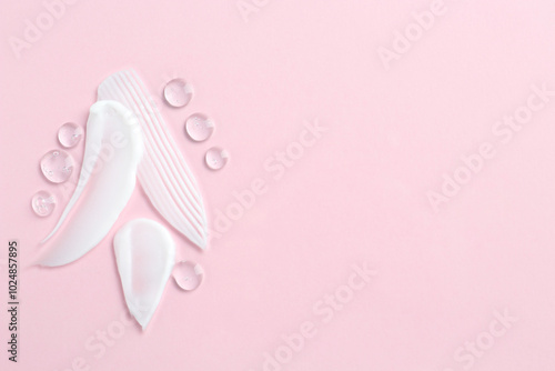 Smears of different cosmetic products on pink background, top view. Space for text