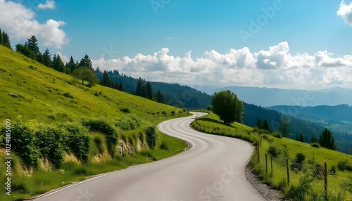 A winding road through a lush, green valley surrounded by mountains under a cloudy sky