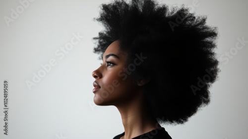 Profile of a young woman with natural hair, side view against a plain background, minimalistic portrait.